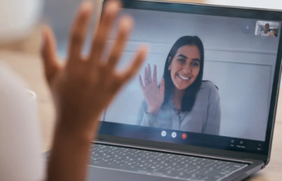 A woman on a computer screen waving and a hand waving in response.