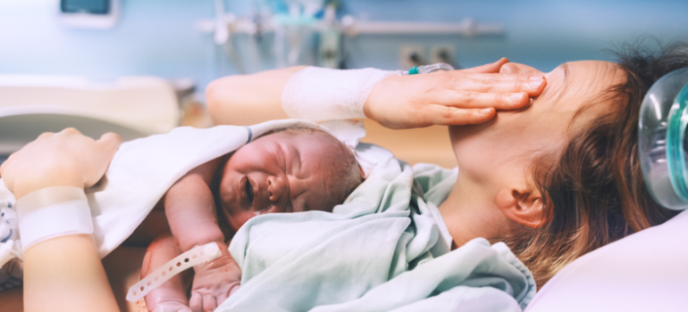 A woman on a hospital bed holding a new baby. 