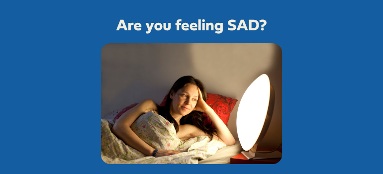A woman lies in bed with a light therapy lamp. (Getty Images)