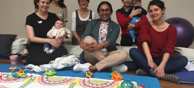 Image of a group of women, some holding babies, all smiling and looking at the camera.