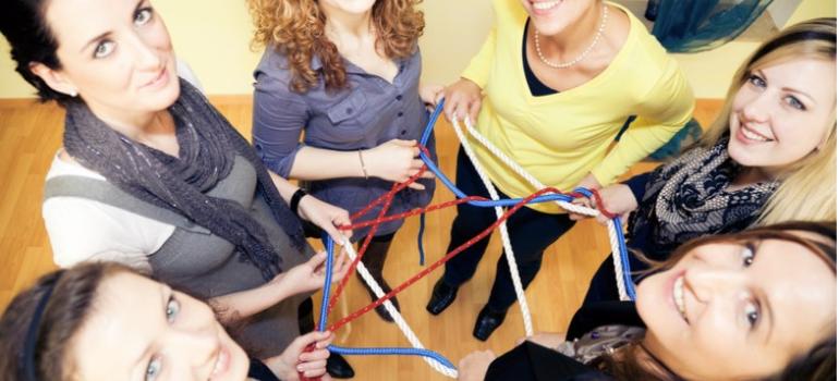 Women standing holding connected ropes; showing networking and working together